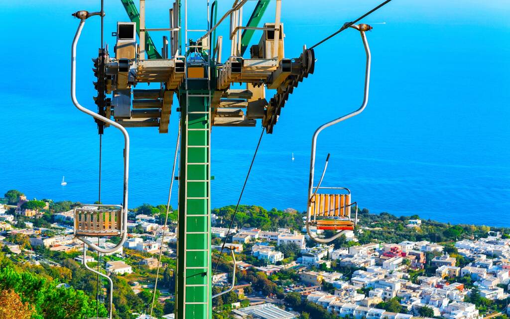 Chair lifts in Capri Island town at Naples in Italy. Landscape with deck chairs and Blue Mediterranean Sea at Italian coast. Anacapri in Europe. View on summer. Amalfi scenery. Holiday and vacation.