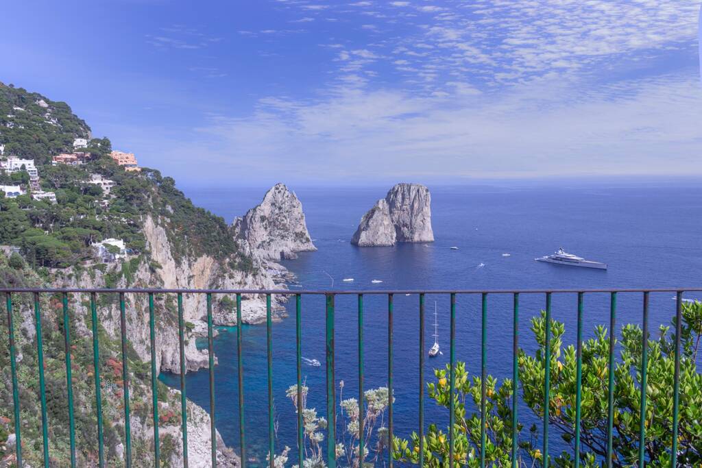 Panoramic view of famous Faraglioni Rocks, most visited travel attraction of Capri Island, Italy. Beautiful paradise landscape with azure sea in summer sunny day.