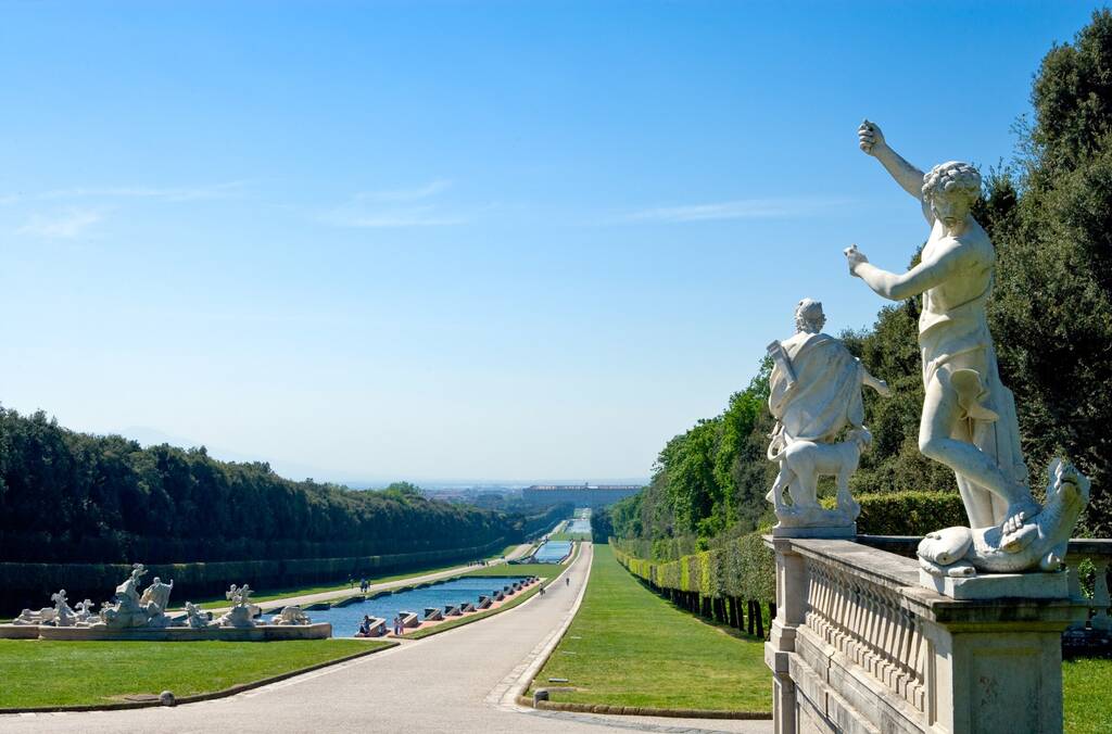 Italy, Caserta, panoramic view of the park of the Royal Palace with marble statue in the foreground