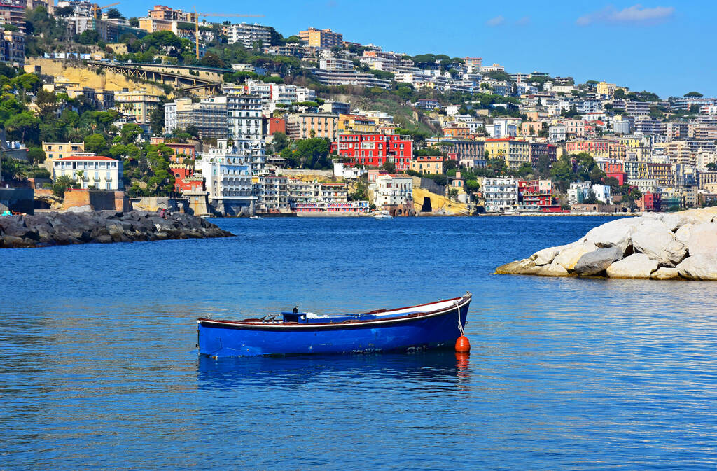 Italy, Naples, fishing boat in the small port of Riva Fiorita with Posillipo hill in the background.