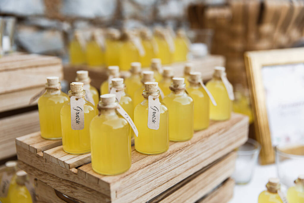 Bottles of limoncello on wooden stands. Closed with corks. Inscriptions in Italian "thank you"
