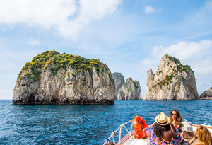 CAPRI, ITALY - MAY 08, 2015 : Unknown  tourists on cruise boat in front of  Fraglioni rocks close to the isle of Capri, Italy.