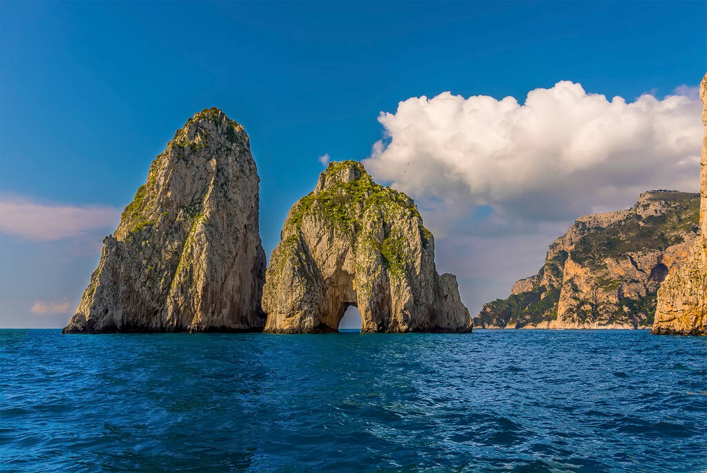 Cumulus clouds hover over the Faraglioni rocks on the eastern side of the Island of Capri, Italy 