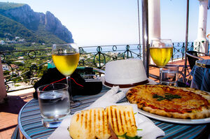 Light lunch with toasts and white wine and italian pizza with a view of the sea at Capri Island, Italy
