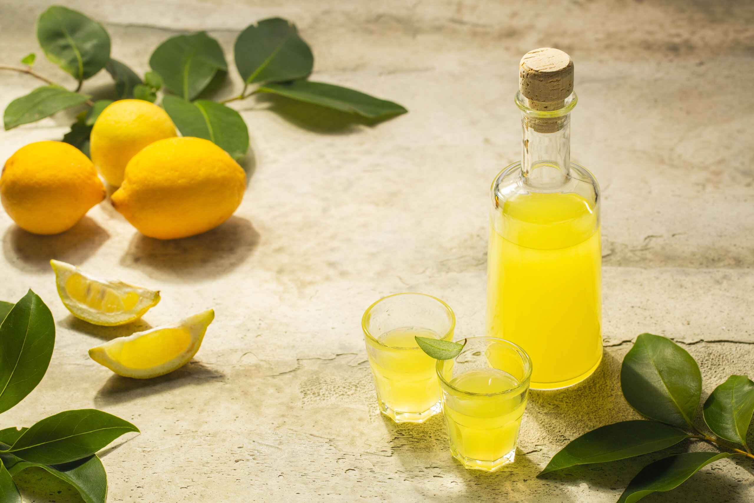 Limoncello w małych kieliszkach i butelce - włoski likier cytrynowy, cytryny, licencja: shutterstock/By OlgaBombologna