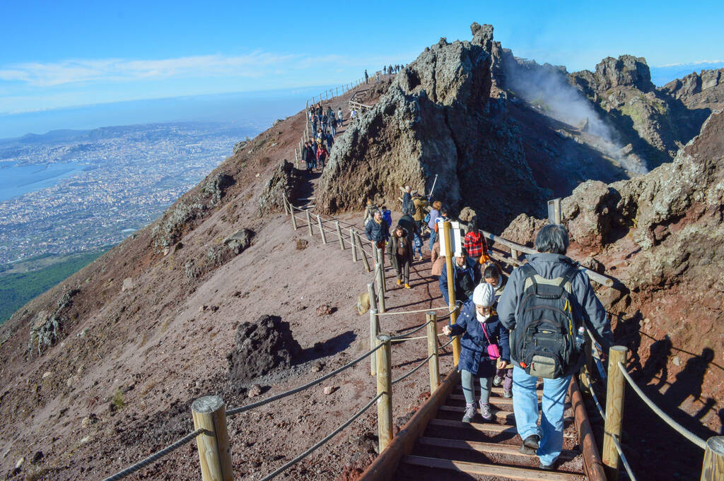 Tourists visiting Mount Vesuvius volcano. Beautiful view of the top with blue sky landscape in a sunny day and the city behind.  Naples/ Metropolitan City of Naples / Italy -12/28/2013