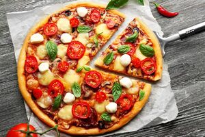 Świeża pizza z pomidorami, serem i grzybami na drewnianym stole zbliżenie