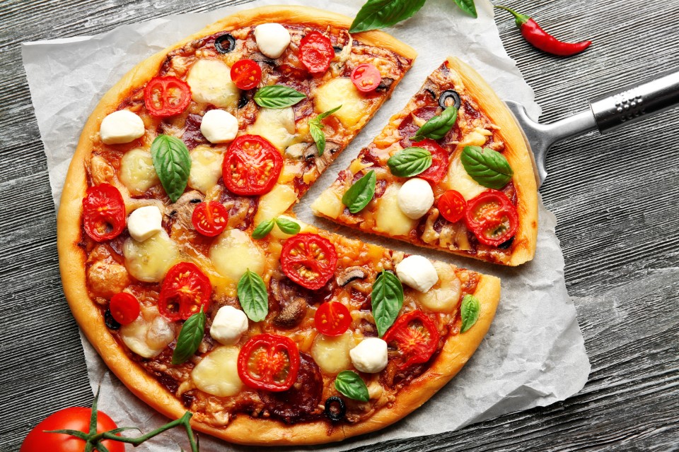 Świeża pizza z pomidorami, serem i grzybami na drewnianym stole zbliżenie
