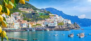 Plan podróży po Wybrzeżu Amalfi. Panoramiczny widok na piękne Amalfi na wzgórzach prowadzących w dół do wybrzeża, Kampania, Włochy. Wybrzeże Amalfi jest najpopularniejszym miejscem podróży i wypoczynku w Europie. Dojrzałe żółte cytryny na pierwszym planie.