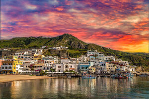 sunset on higgledy-piggledy piled houses on bay of Ischia island, Naples in Italy