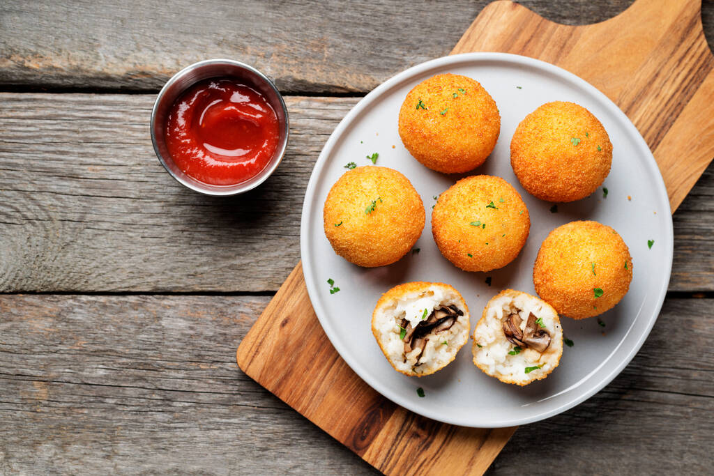Homemade Fried Risotto Arancini stuffed with mushroom and parmesan cheese, served with tomato sauce.top view